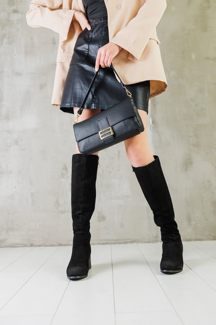 Close-up of female legs in black leather boots. Women's winter shoes. Warm women's boots. Women's modern shoes