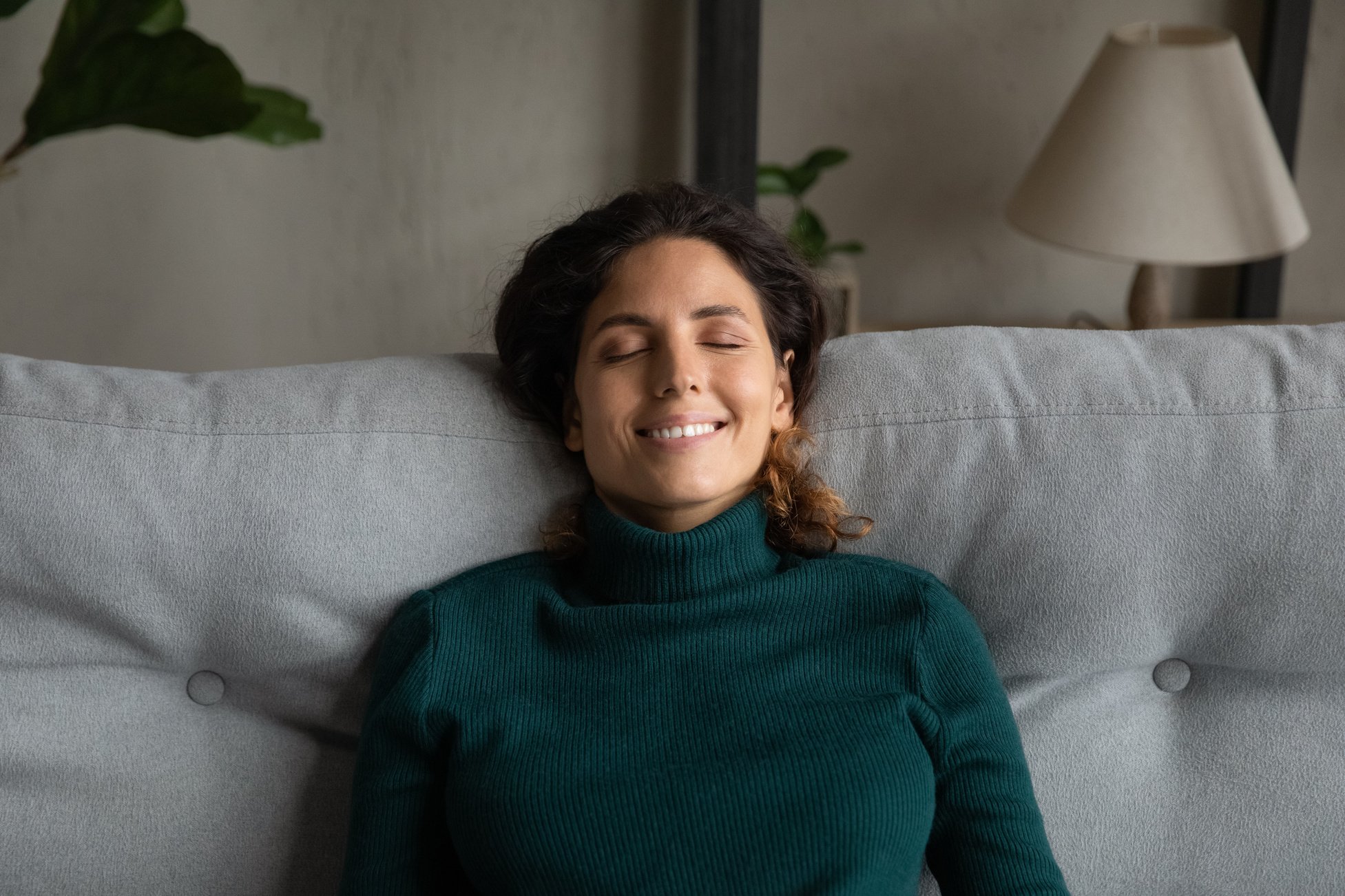 Happy woman rest on couch relieving negative emotions